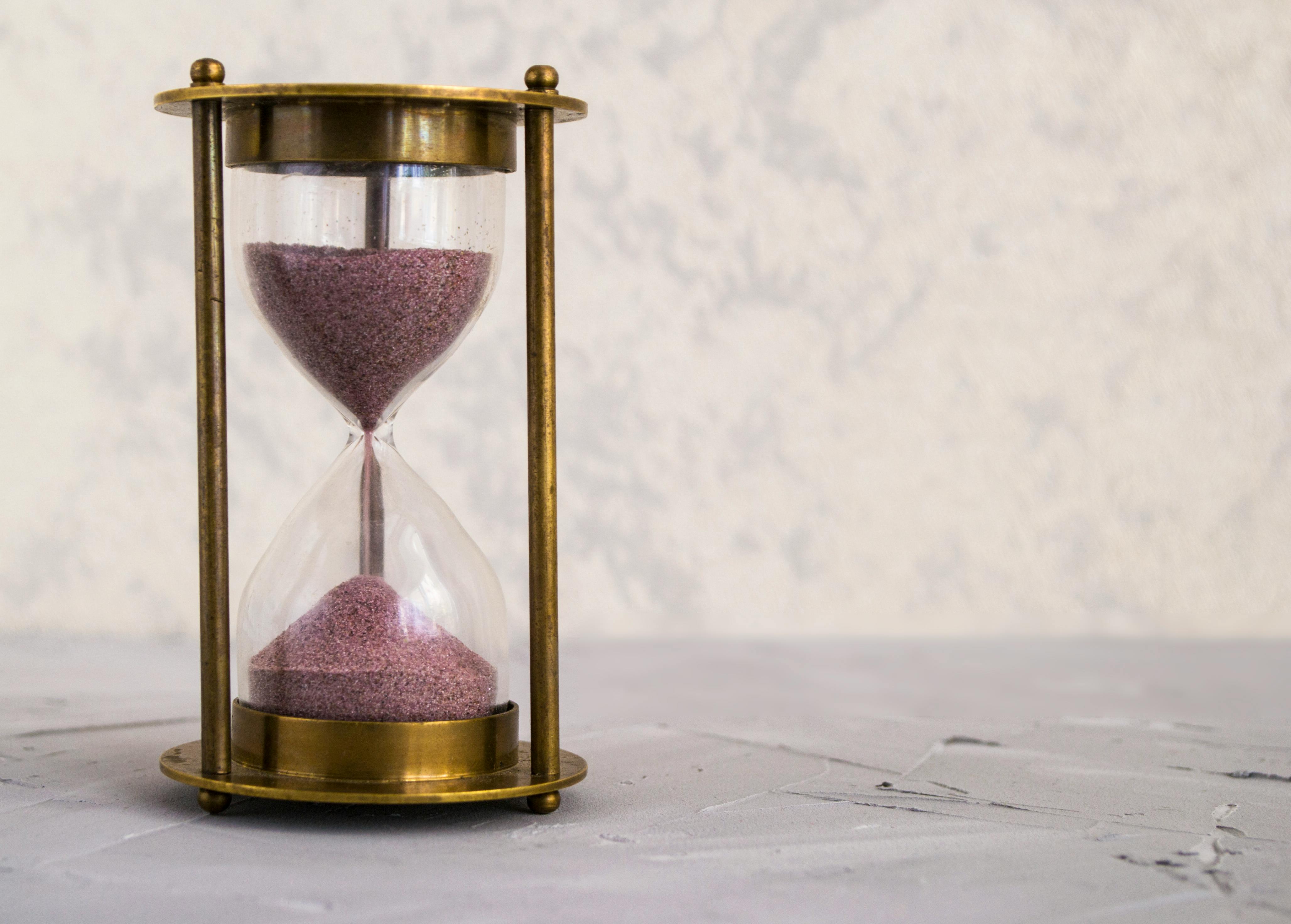 ¿Por qué mi empresa no vende por internet si en persona sí? | Gulupa Digital Reloj de arena sobre escritorio: metáfora del tiempo de respuesta y la fricción en el proceso de venta.