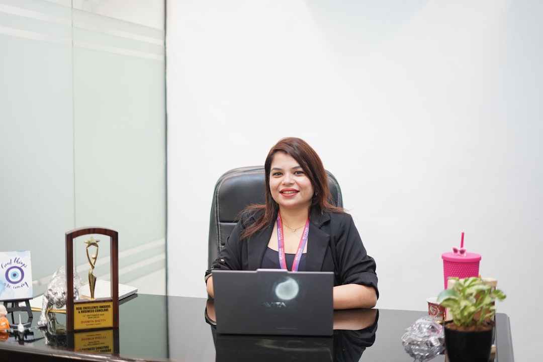 Mujer sentada en escritorio con portátil en ambiente de trabajo