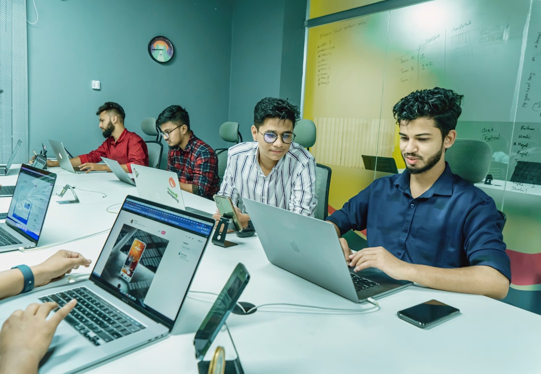 Equipo de trabajo colaborando alrededor de una mesa con laptops para un proyecto nearshore